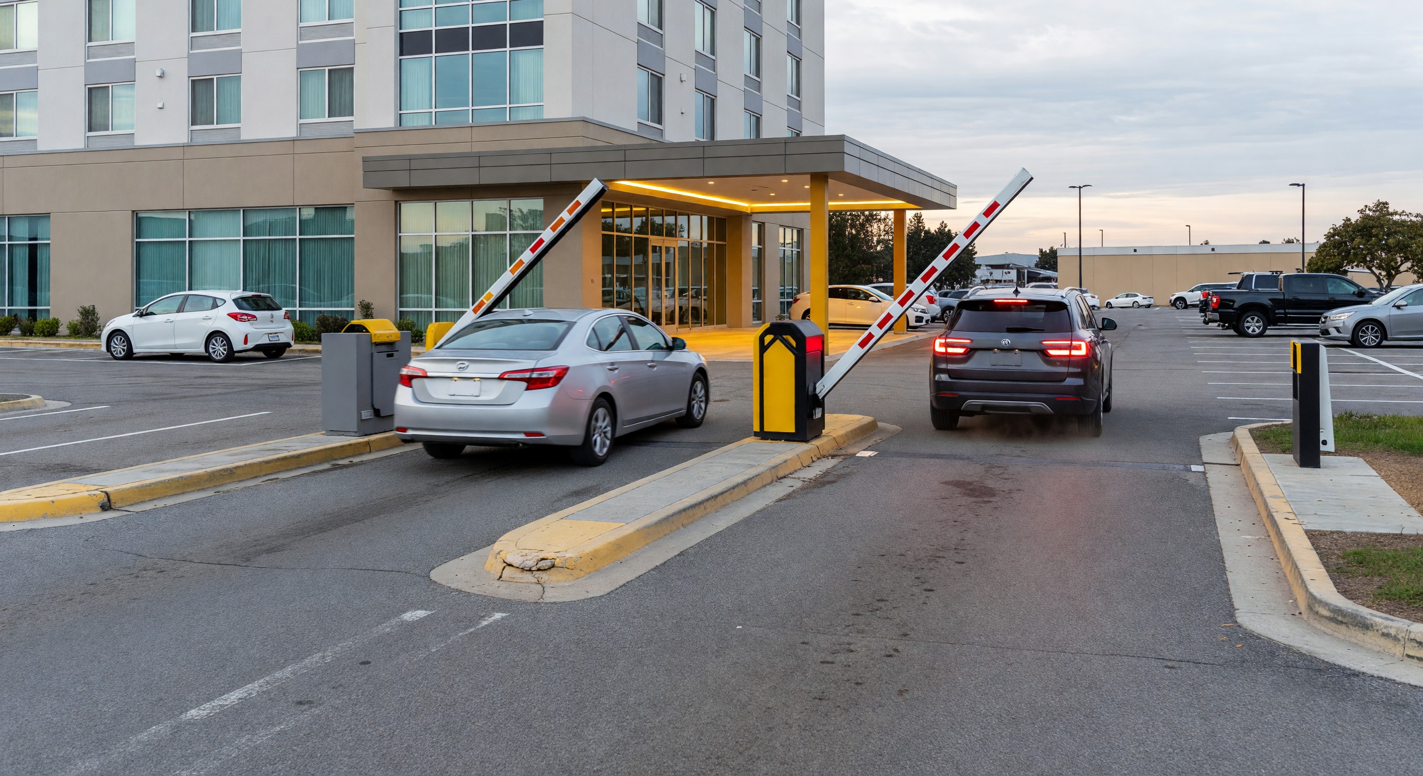 Hotel parking lot with barrier gate system showing vehicles entering and exiting
