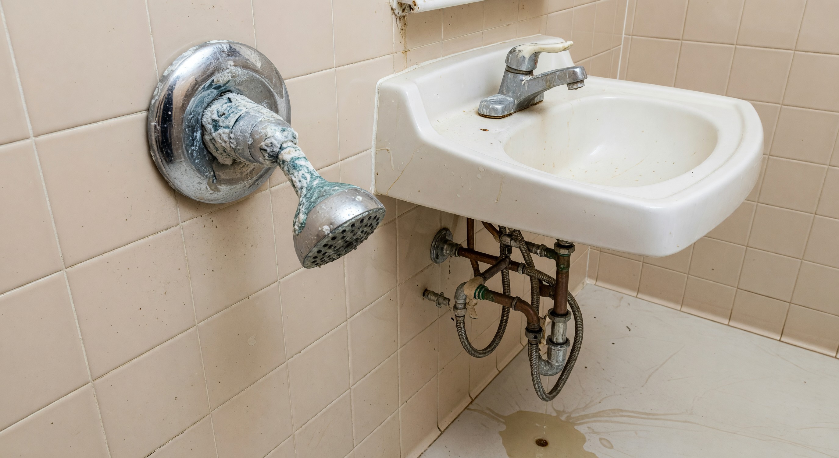 Hotel bathroom plumbing fixtures including showerhead and faucet requiring maintenance
