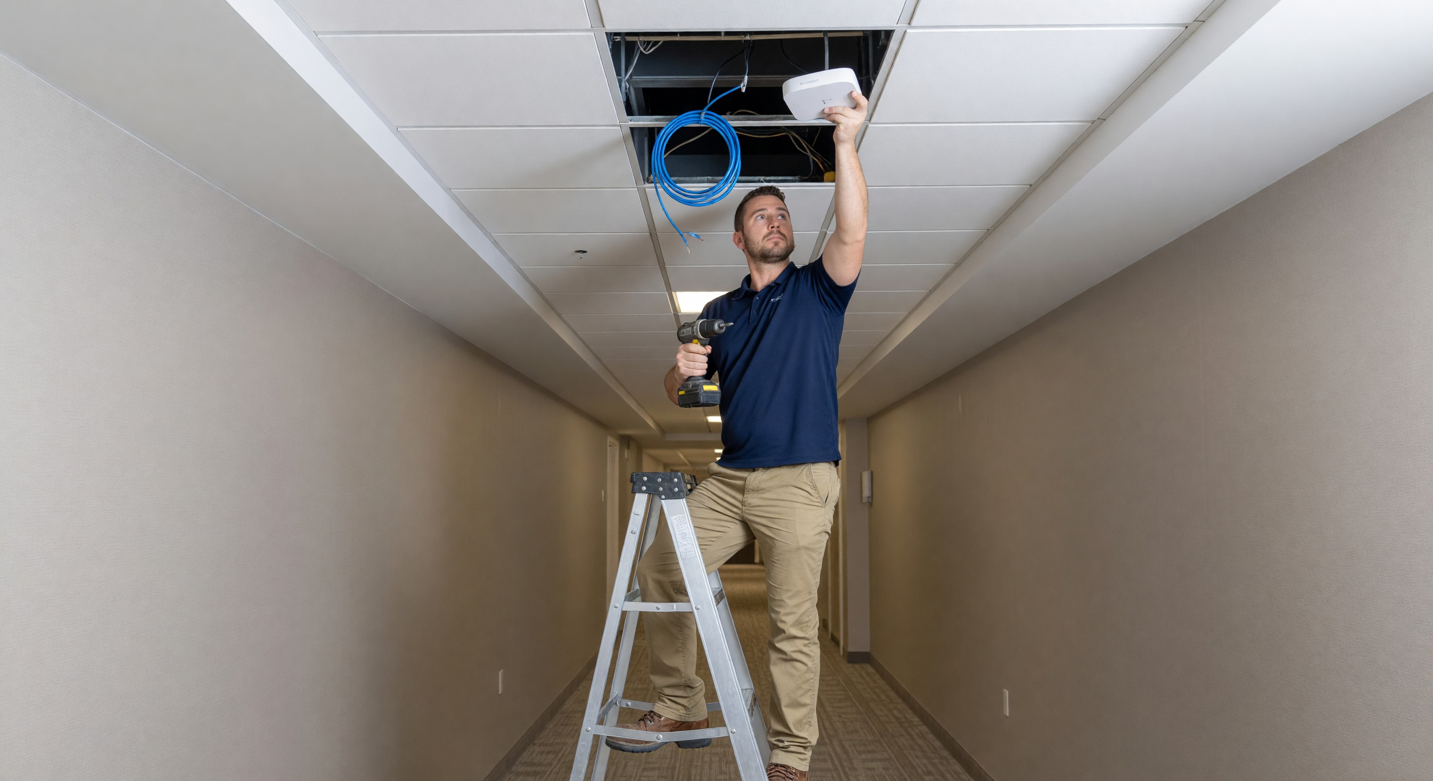 Hotel wireless access point installation in corridor ceiling with technician